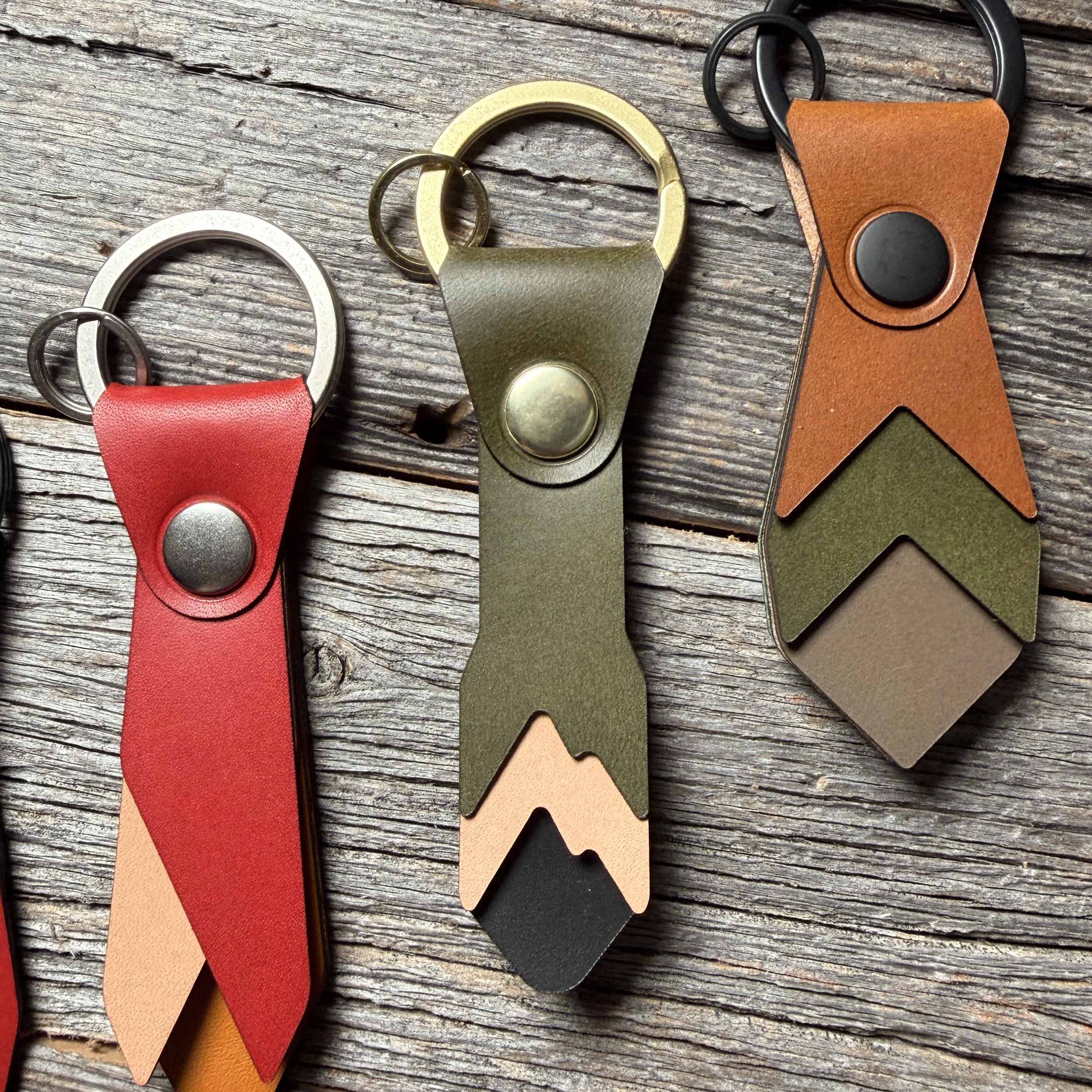 Alpine leather keychain styled on weathered wood beside other Keyway full-grain veg-tan colorways