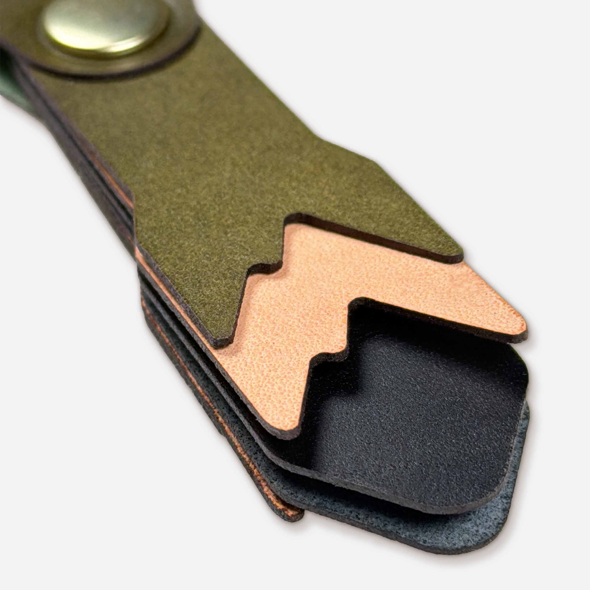 Close-up of Alpine leather keychain showing layered Italian full-grain veg-tan in olive, natural, and black