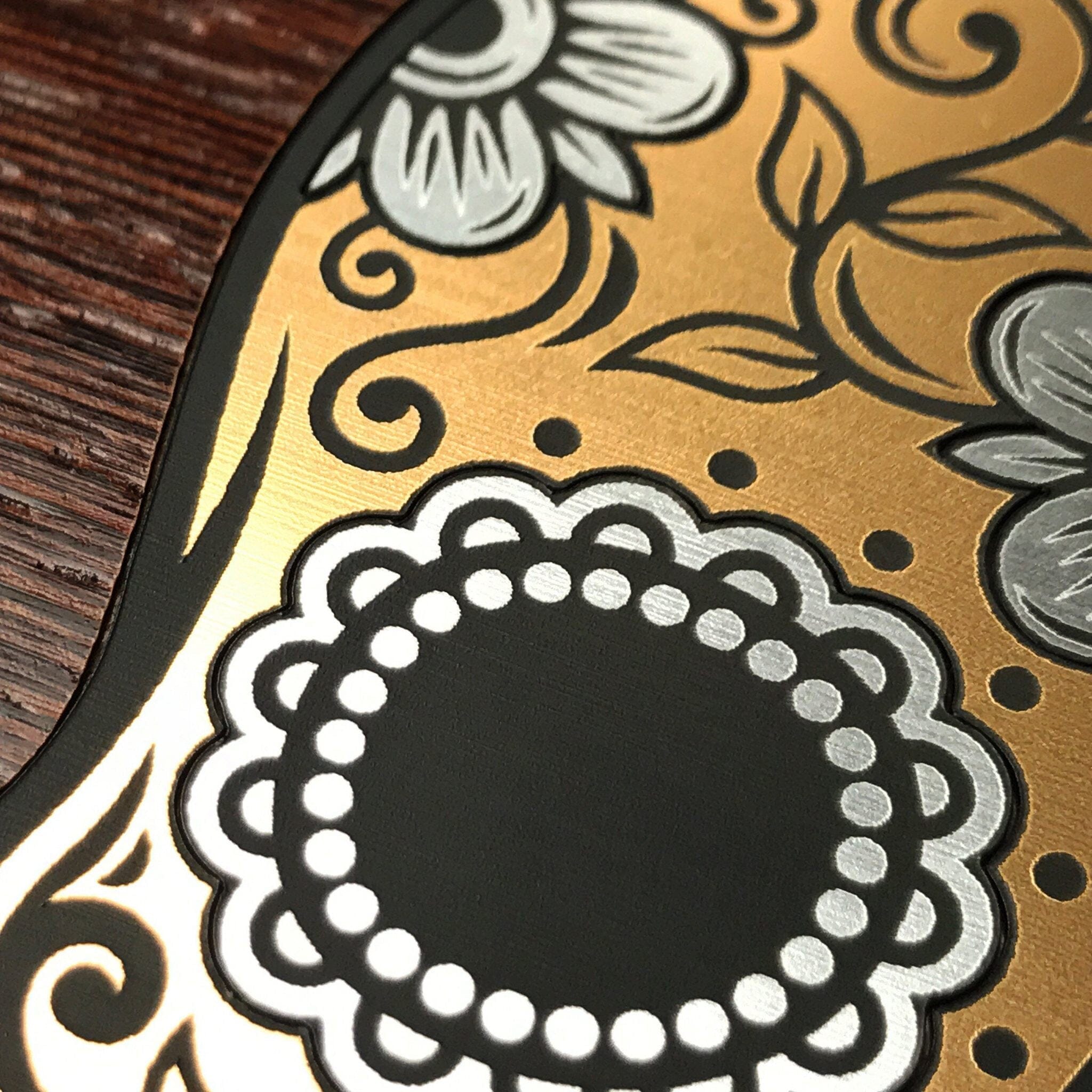 Zoomed in detailed shot #2 of the Calavera Wood Sugar Skull Wood phone case featuring gold and silver engraved metallic inlays