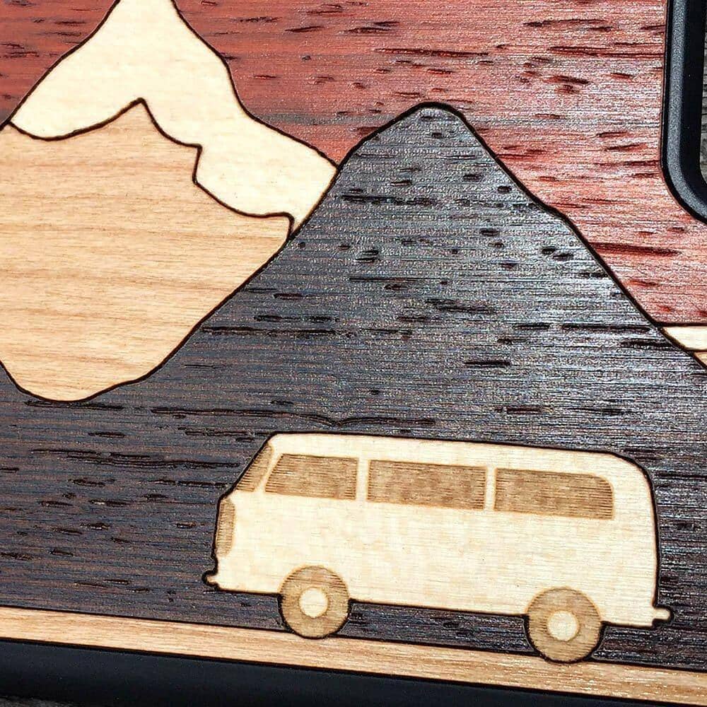 Zoomed in detailed shot of the Cross Country wood phone case by Keyway featuring a Maple camper van traversing mountains cut from Maple, Cherry and Wenge