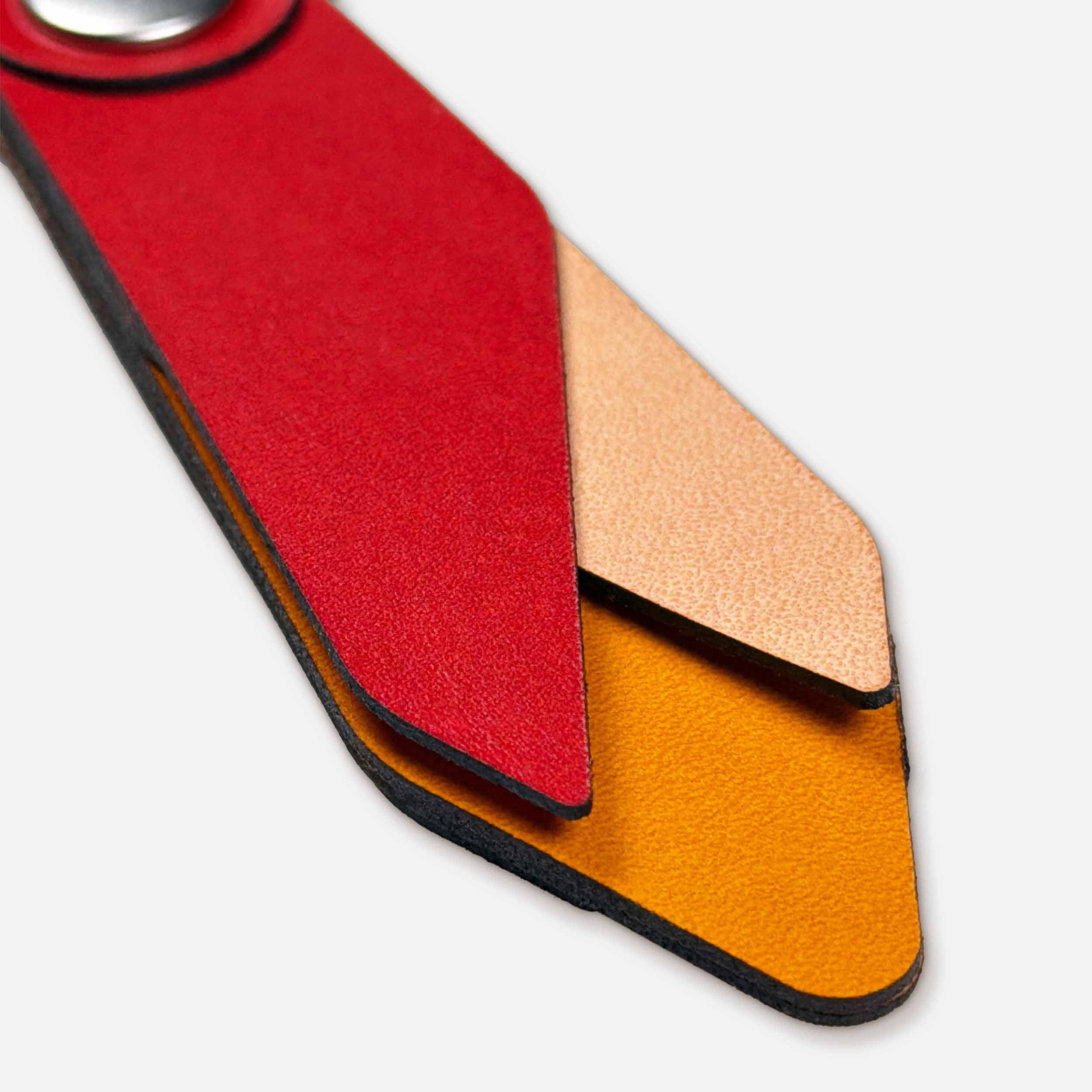 Close-up of Ember leather keychain showing layered Italian full-grain veg-tan in red, natural, and honey