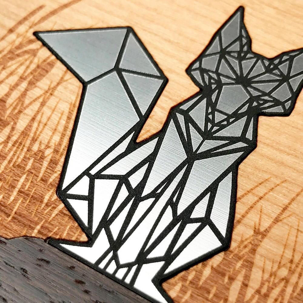 Zoomed in detail shot of the geometric silver fox inlay on engraved cherry wood phone case by Keyway