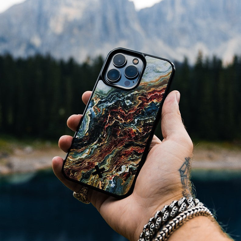Hand holding a phone with a colorful Verona case against a mountainous landscape