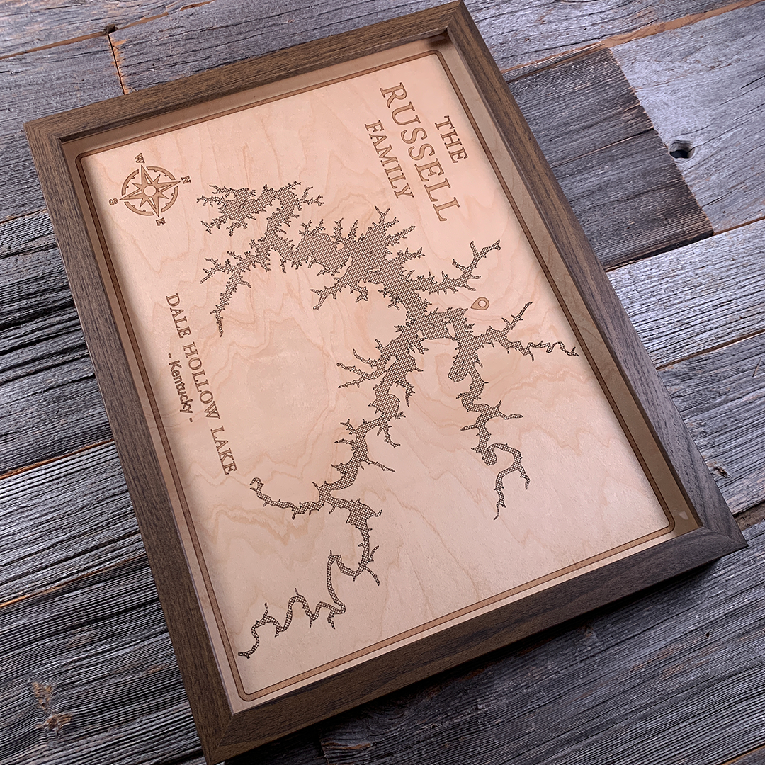 Angled view of personalized framed wood map of Dale Hollow Lake, Kentucky, laser-engraved on maple with a dark wood frame. A beautifully detailed wall art piece designed for lake house décor or custom family gifts.