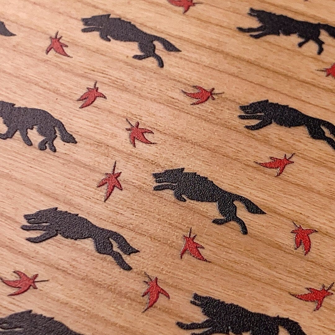 Zoomed in detailed shot of the unique pattern of wolves and Maple leaves printed on Cherry wood iPhone 15 Pro MagSafe Case by Keyway Designs