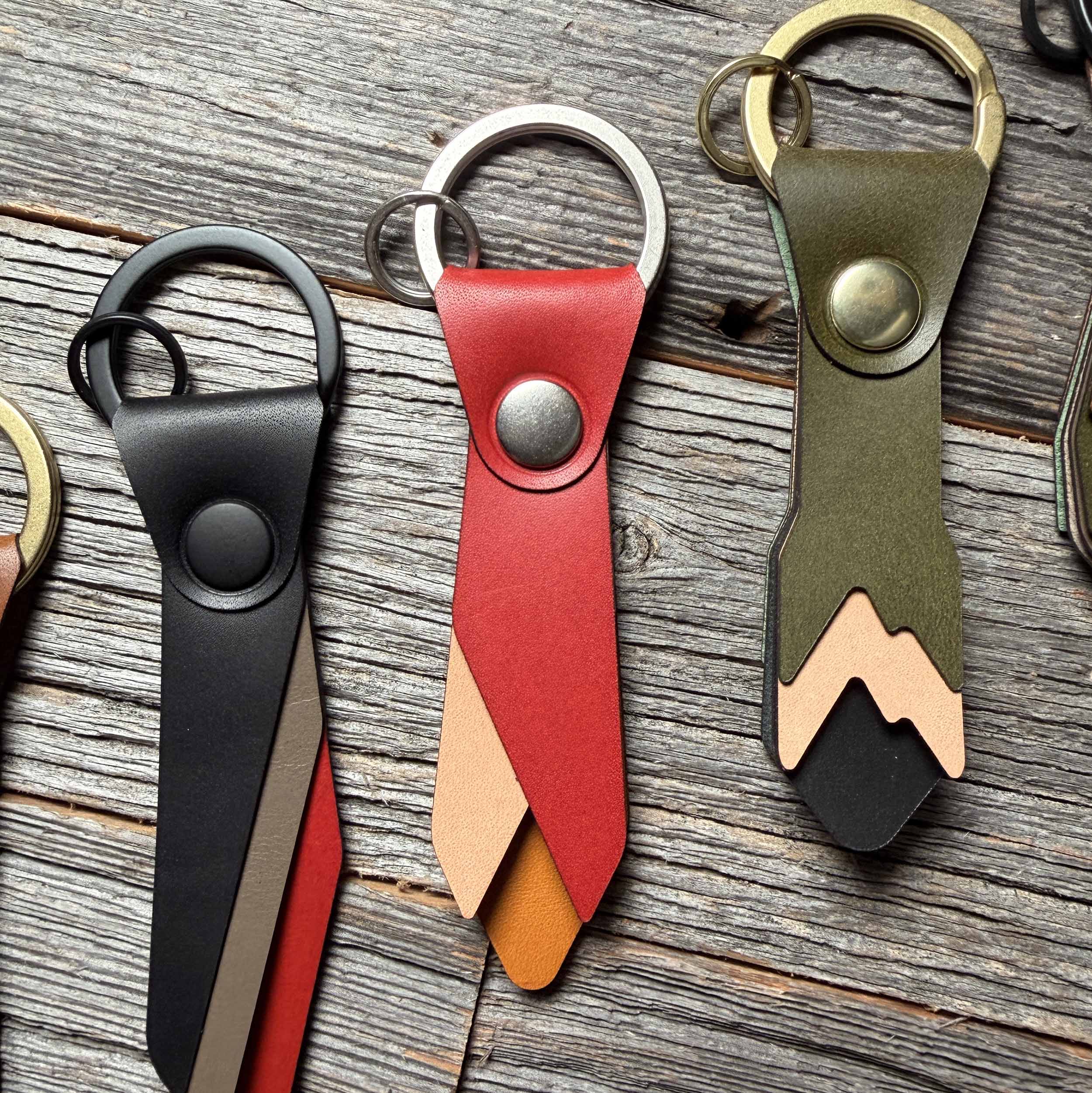 Ember leather keychain styled on weathered wood beside other Keyway full-grain veg-tan colorways