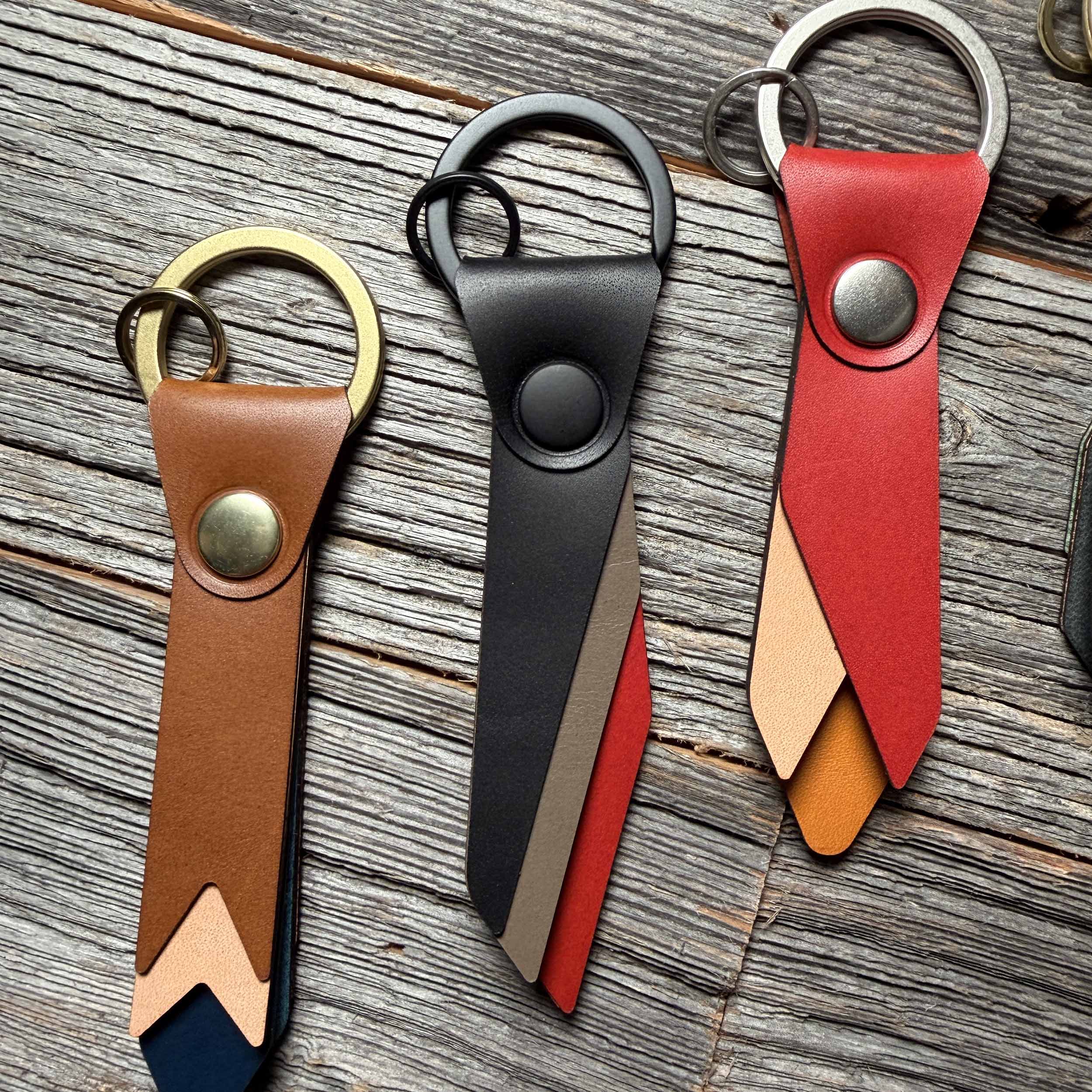 Flint leather keychain styled on weathered wood beside other Keyway full-grain veg-tan colorways