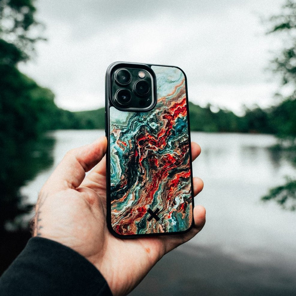 Hand holding a phone with a colorful Verona case against a natural background